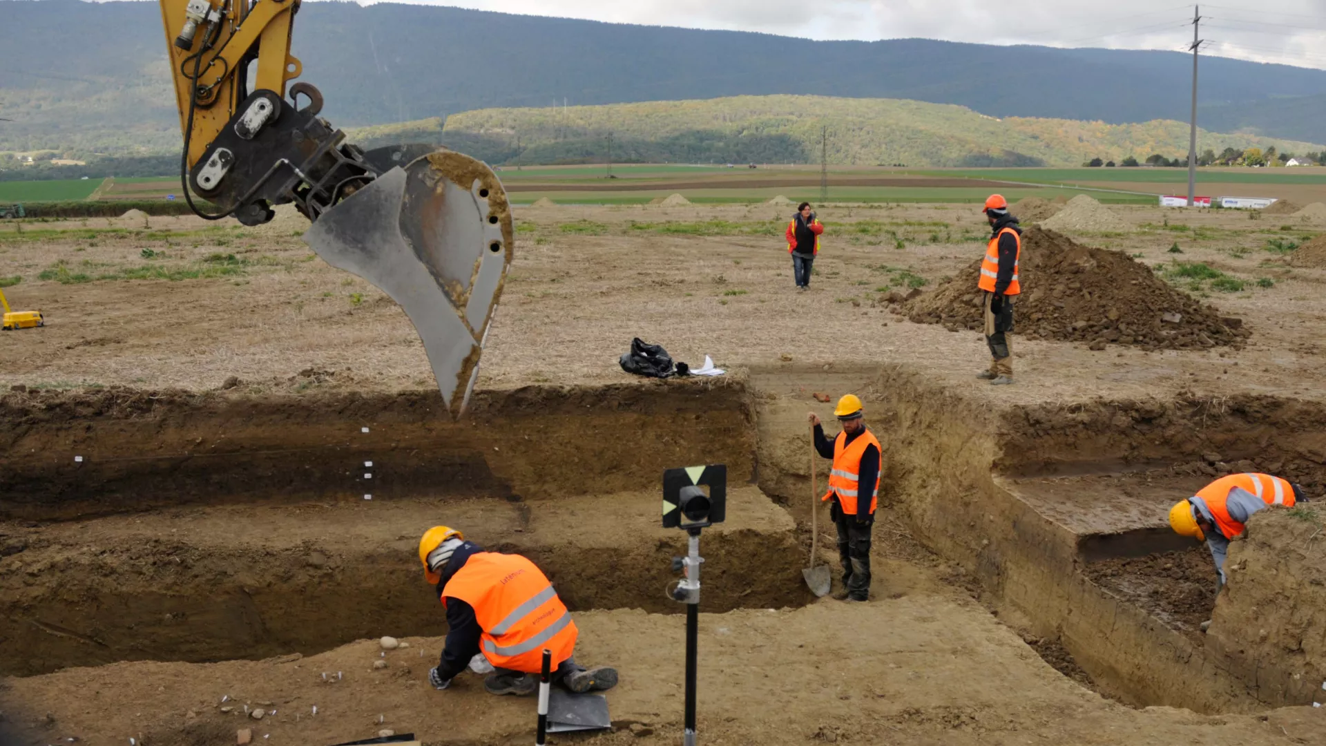 Des archéologues décapent le sol à l'aide d'une pelle mécanique à Marin/Fins de Mange