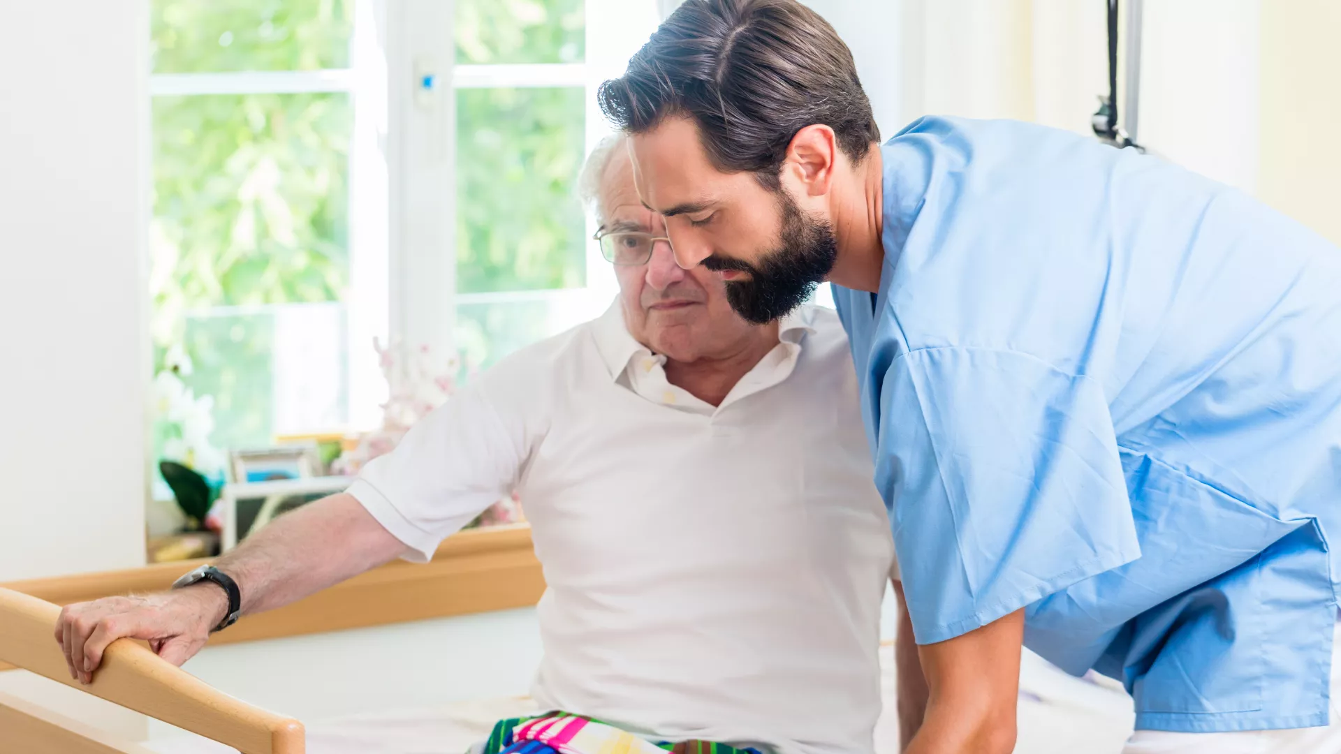 Aide soignant qui aide une personne âgée à se lever de son lit