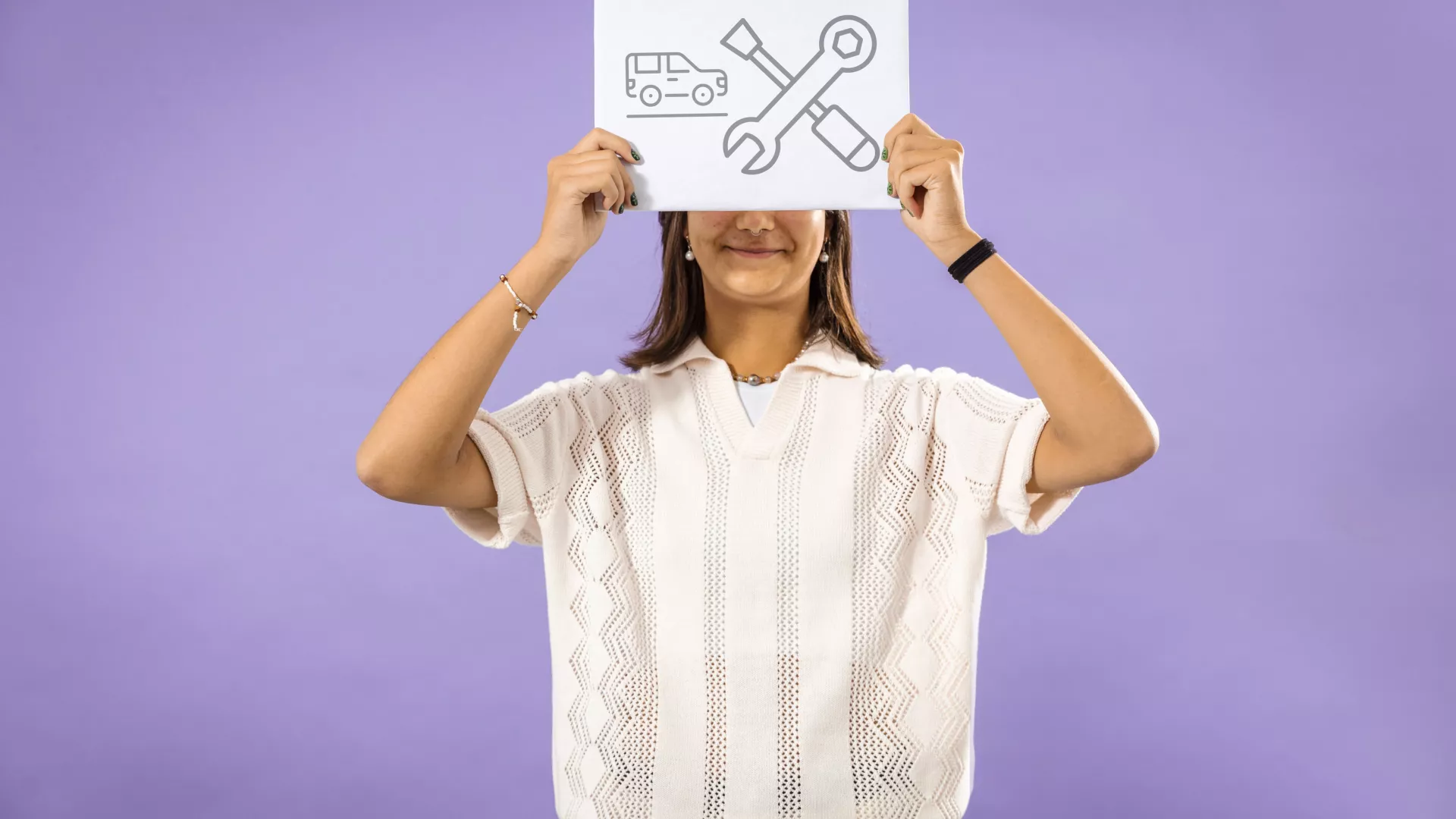 Personne qui tient une pancarte avec des pictogramme de mécanicien en maintenance automonbile 