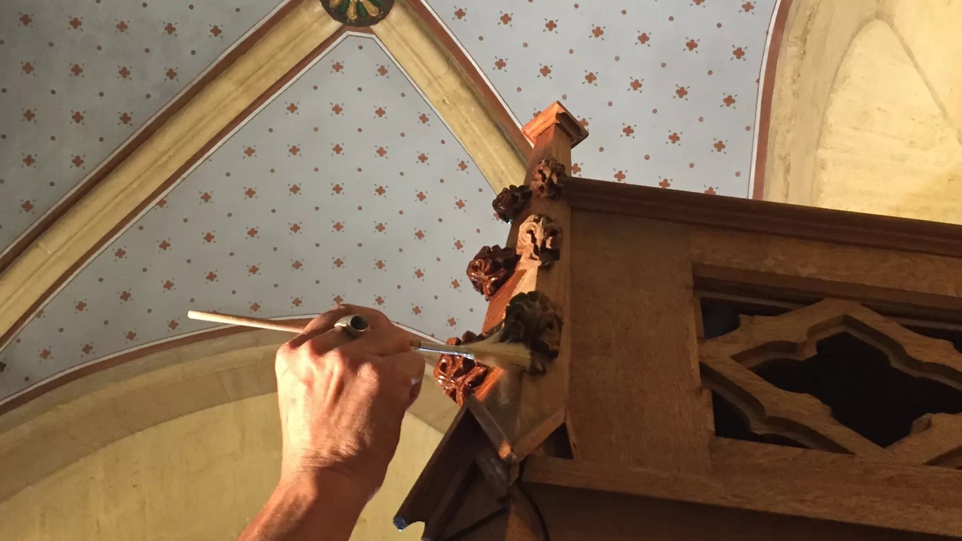 Main effectuant un geste de restauration sur un tambour à la Collégiale de Neuchâtel