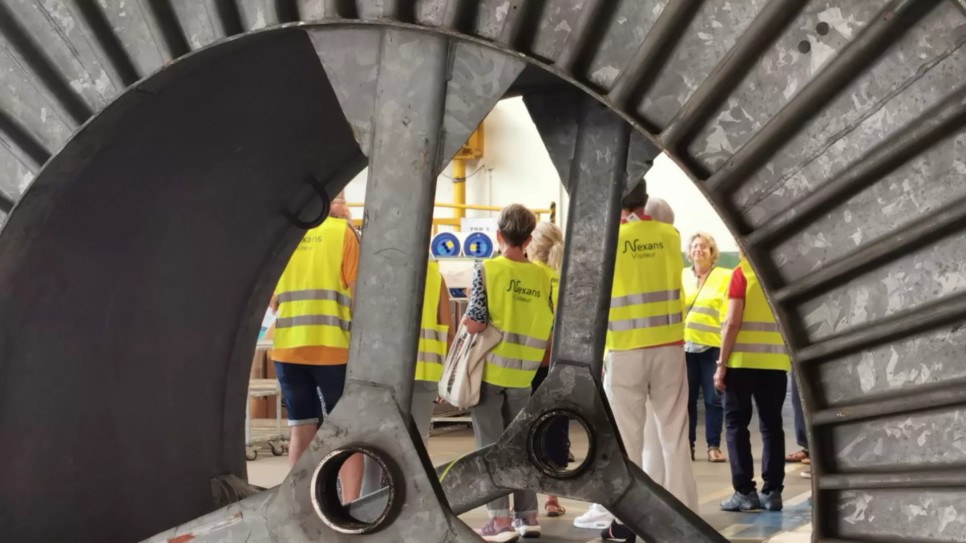 Public des JEP photographié à travers une bobine des câbleries de Cortaillod