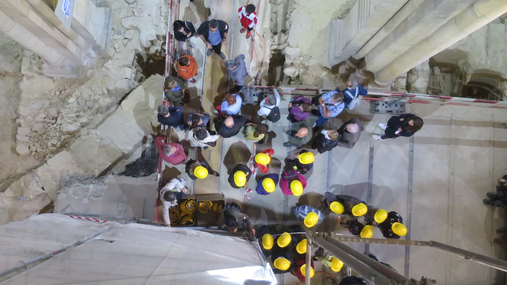 Public coiffé de casques jaunes autour des fouilles de la Collégiale