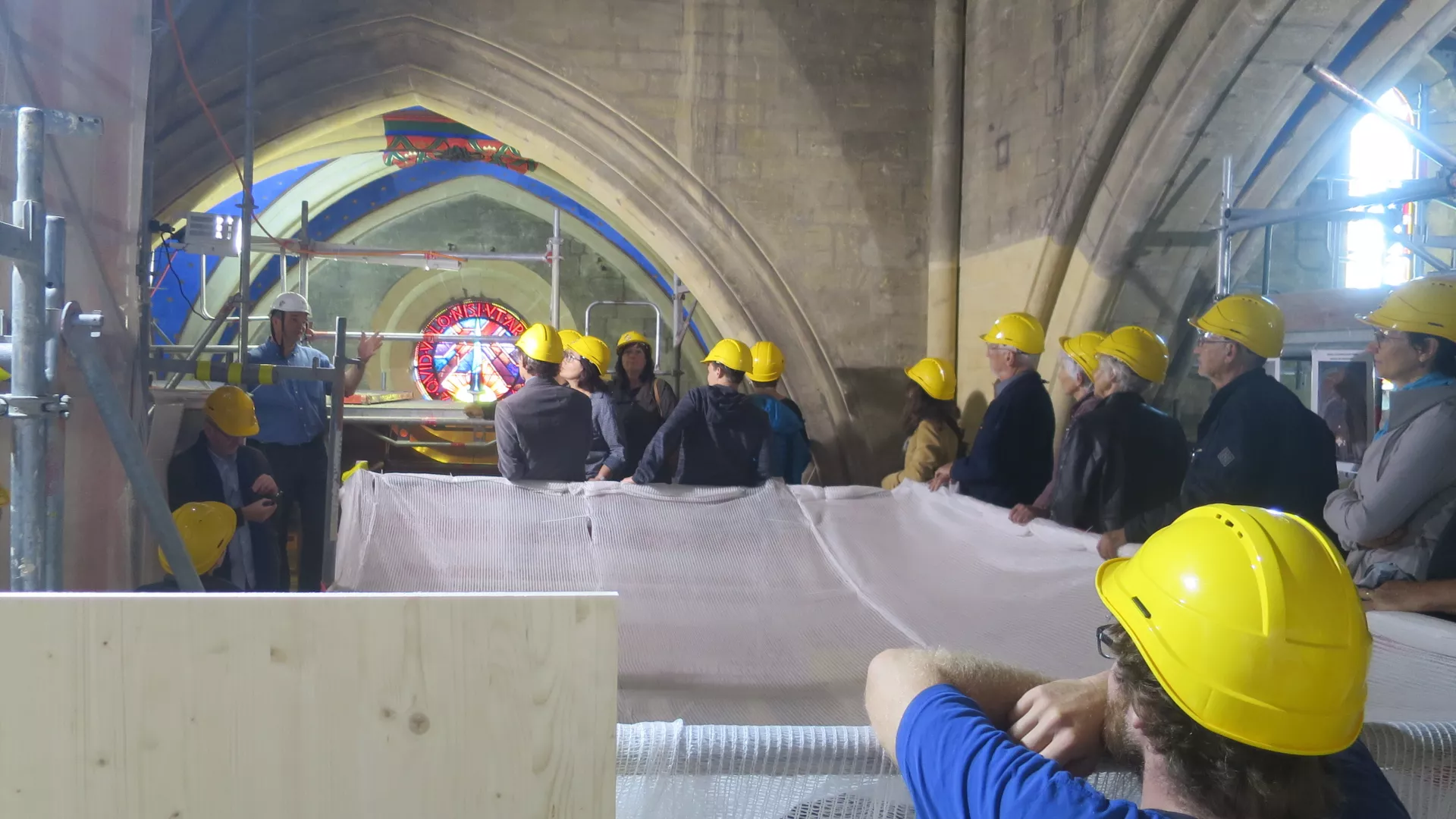Public coiffé de casques jaunes sur les échafaudages de la Collégiale